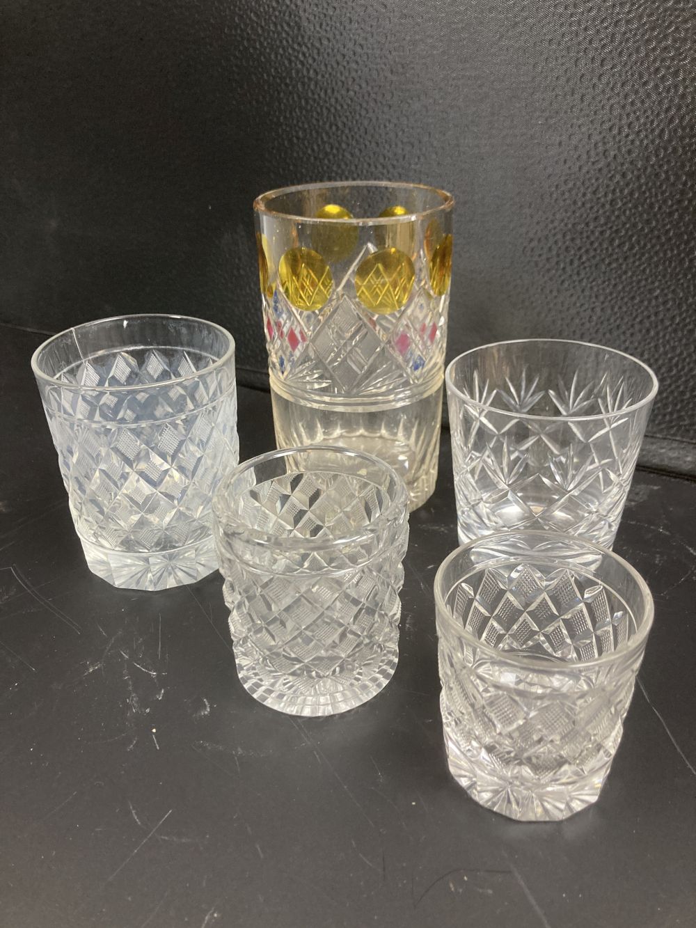 Five cut glass tumblers, the largest with enamelled panels, 13.5cm